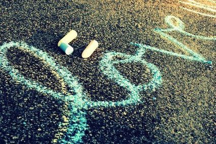 Kawa�ki kolorowej kredy le��ce na asfalcie obok napisu wykonanego niebiesk� kred�