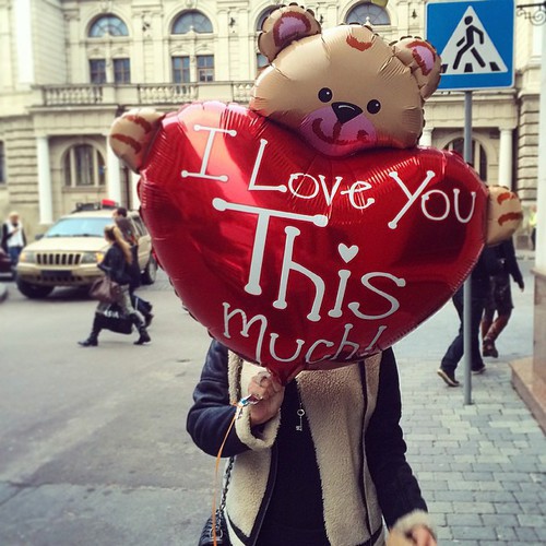 Kobieta trzymaj�ca du�y czerwony balon w kszta�cie serca z napisem I Love You This Much i misiem
