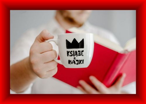 M�czyzna w jasnej koszuli trzyma bia�y kubek z napisem Ksi��� z bajki i ksi��k�