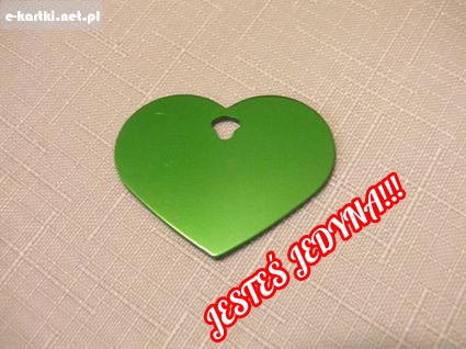 Zielony metalowy wisiorek w kszta�cie serca z otworem na jasnym obrusie z napisem Jeste� jedyna