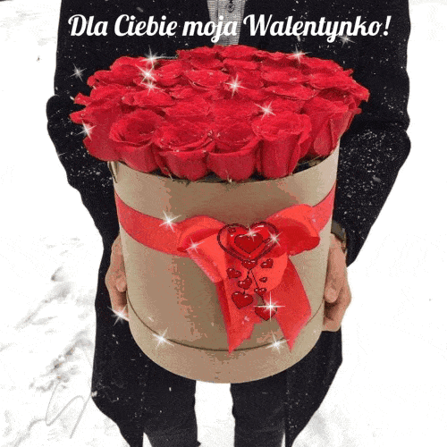 M�czyzna trzyma okr�g�e pude�ko pe�ne czerwonych r� przewi�zane wst��k� z sercami i napisem