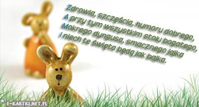 Dwa ceramiczne zajączki wielkanocne w trawie oraz życzenia świąteczne na białym tle