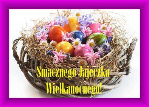 Wiklinowy koszyk z kolorowymi pisankami, sianem i wiosennymi kwiatami oraz napisem Smacznego Jajeczka Wielkanocnego