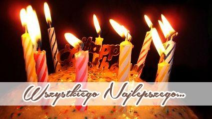 P�on�ce kolorowe �wieczki na urodzinowym torcie z napisem Wszystkiego Najlepszego na ciemnym tle