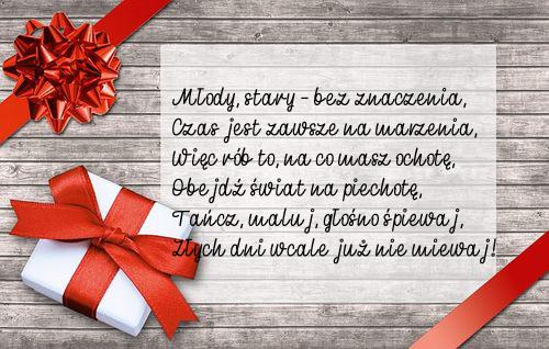 Prezent z czerwon� wst��k� i kokard�, drewniane t�o, bia�a karteczka z wierszem urodzinowym