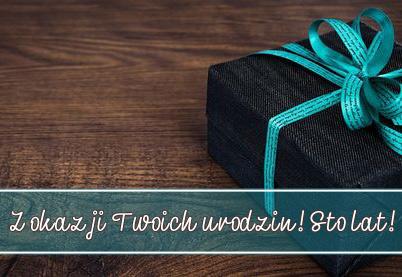 Czarne pude�ko prezentowe z turkusow� wst��k� na drewnianym tle z napisem Z okazji Twoich urodzin! Sto lat!