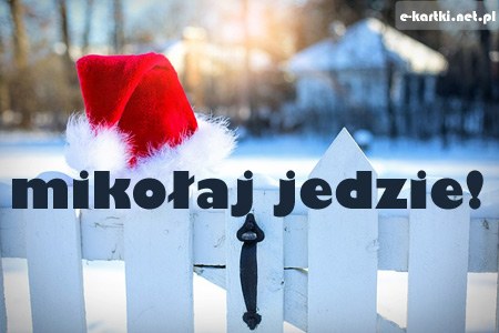 Czerwona czapka Miko�aja usadowiona na drewnianym p�ocie w zimowej scenerii