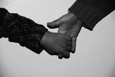 Czarno-bia�e zdj�cie przedstawiaj�ce d�o� dziecka trzymaj�c� r�k� doros�ej osoby